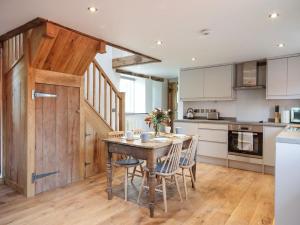 uma cozinha com mesa e cadeiras e uma porta de madeira em The Cider Barn em Flaxley