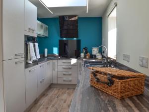 una cocina con armarios blancos y una pared azul en 1 Barnagh Barn, en Kirkmichael