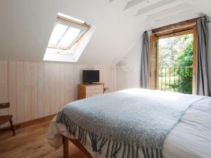 a white bedroom with a bed and a window at The Cider Barn in Flaxley
