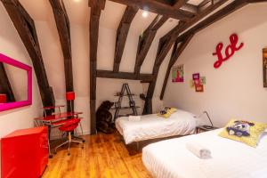 two beds in a room with wooden floors and beams at Les Chambres du "Coup de Coeur de Sarlat" in Sarlat-la-Canéda