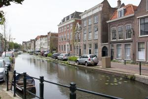 a canal in a city with cars parked next to buildings at Canal House in Historic City Center Gouda in Gouda
