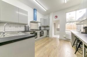 a large kitchen with white appliances and a large window at A beautiful newly renovated home: The Arlingford in London