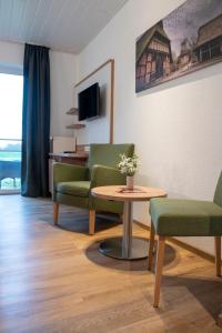 uma sala de espera com cadeiras, uma mesa e uma televisão em Hotel Am Deich em Apen
