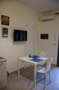 einen weißen Tisch mit 2 Stühlen und einen TV an der Wand in der Unterkunft Trinacria apartments in Catania