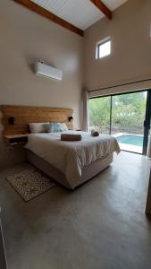 a bedroom with a large bed and a large window at Hyena Den - Marloth Park in Marloth Park