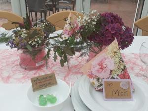 a table with plates and flowers and cards on it at Hotel Am Deich in Apen