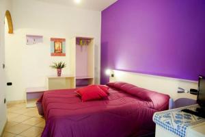 een paarse slaapkamer met een groot bed met rode kussens bij Affittacamere Casa del Sole in Cala Gonone