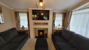 a living room with two couches and a fire place at LUXURY LODGE on edge of New Forest and 800m from sea ENTERTAINMENT and LEISURE PASSES INCLUDED in Milford on Sea