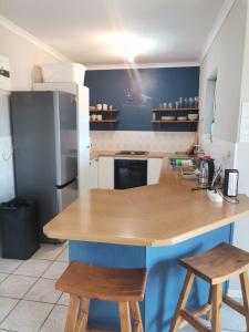 a kitchen with a wooden counter with two stools at Villa De Vie Self Catering Apartment in Brackenfell