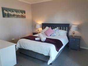 a bedroom with a large bed with pink and white pillows at Villa De Vie Self Catering Apartment in Brackenfell +7 photos