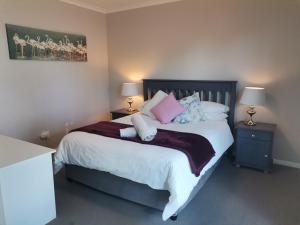 a bedroom with a large bed with pink and white pillows at Villa De Vie Self Catering Apartment in Brackenfell