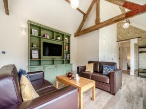 a living room with leather furniture and a tv at The Cart House in Hatherop