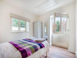 a white bedroom with a bed and two windows at The Cart House in Hatherop
