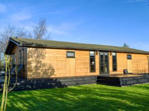 a small wooden house with a grass yard at Appletree Lodge in Wilberfoss