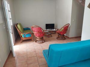 ein Wohnzimmer mit Stühlen, einem Tisch und einem Sofa in der Unterkunft UNE SEULE ENVIE, CELLE D'Y REVENIR in Les Anses-dʼArlets