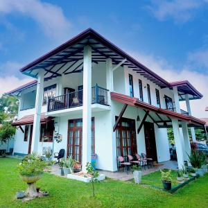 a white house with a balcony and a yard at Howick Residence in Katunayake