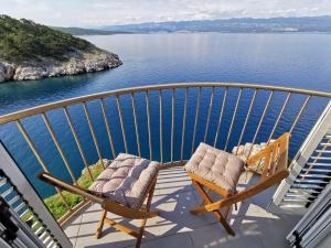 a balcony with two chairs and a view of the water at Vila Verbana Apartments in Vrbnik