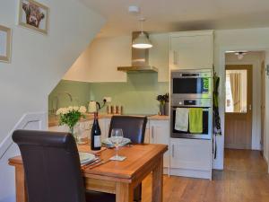 a kitchen with a wooden table with a bottle of wine at Little Cottage in Wigtown