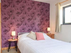 um quarto com uma parede roxa com uma cama e 2 candeeiros em Hill View Lodge em Knucklas