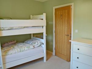 a bedroom with two bunk beds and a door at Durdrich Cottage in St Margarets at Cliff