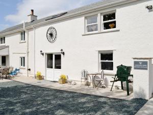 a white house with a patio with chairs and a clock at Greengill Farm Holiday Cottage - Ukc2768 in Gilcrux
