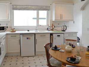 a kitchen with white cabinets and a table and a sink at Mountain View in Silloth