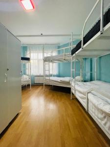 a room with three bunk beds and a wooden floor at Hostel Akacia in Shymkent