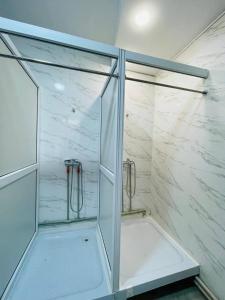 a shower with glass doors and a marble wall at Hostel Akacia in Shymkent