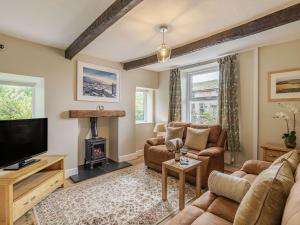 a living room with a couch and a tv and a fireplace at Lane Ends Cottage in Disley