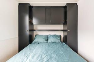 a bed with a black headboard and blue sheets at Valkenbosch - De Pimpel 12 in Oisterwijk