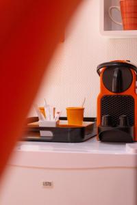 - une cafetière orange installée au-dessus d'un réfrigérateur dans l'établissement Les Chambres du "Coup de Coeur de Sarlat", à Sarlat-la-Canéda