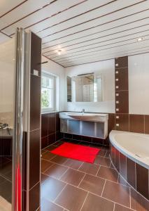 ein Badezimmer mit einer Badewanne, einem Waschbecken und einem roten Teppich in der Unterkunft QUARTIER 179 in Schladming
