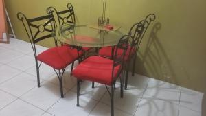 a glass table and four chairs with red seats at Pearl of the City NEW KINGSTON in Kingston