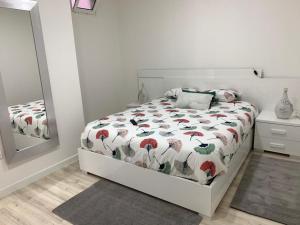 a bedroom with a bed with a comforter and a mirror at Pérola de Gil Vicente Duplex in Setúbal