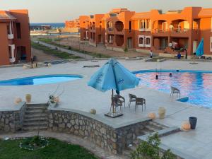 una sombrilla azul y sillas junto a la piscina en Chalet Amexico Paradise - Ain Sokhna, en Ain Sokhna