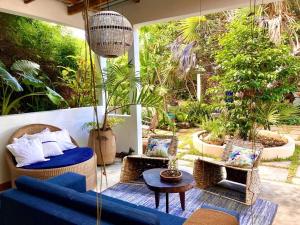 a patio with a blue couch and chairs and plants at Hakha Beach House in Praia do Tofo