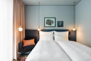 una habitación de hotel con una cama grande y una silla en Hotel Galántha, en Eisenstadt