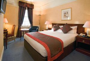 a hotel room with a large bed and a desk at Old Hunstanton Le Strange Arms Hotel in Hunstanton