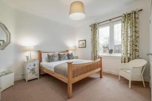 ein Schlafzimmer mit einem Bett, einem Stuhl und einem Fenster in der Unterkunft Heather Cottage, 2 bedroom in Comrie in Comrie