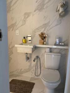 a bathroom with a toilet and a shelf on the wall at Praia do Forte Condomínio Bali Bahia Apt105 in Praia do Forte