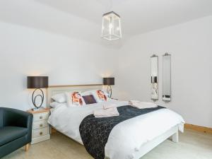 a white bedroom with a bed and a chair at Nesting Box in Chapel Saint Leonards