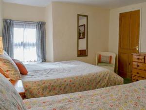 1 dormitorio con 2 camas, vestidor y ventana en The Bridge Inn Apartment en Bridgerule