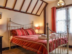 a bedroom with a metal bed with red sheets and a window at Heritage Lodge in Rhyl