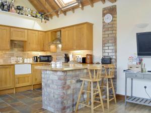 a kitchen with wooden cabinets and a brick wall at Barley Edge in Hornsea
