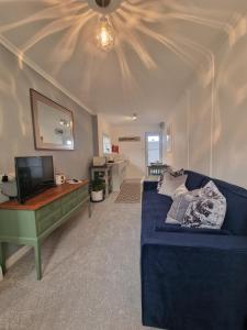 a living room with a blue couch and a television at Small Cottage close to Carbis Bay Beach & St Ives in Carbis Bay