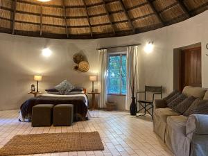 a bedroom with a bed and a couch in a room at Palala River Cottages in Vaalwater