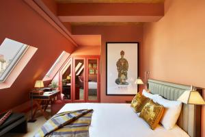 パリにあるHotel de Montesquieuのオレンジ色の壁のベッドルーム1室、ベッド1台が備わります。
