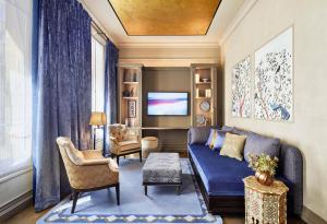 un soggiorno con divano blu e TV di Hotel de Montesquieu a Parigi