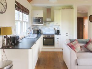 a kitchen with white cabinets and a white couch at Farragon Cottage in Foss