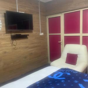 a living room with a tv and a white chair at HPLagos in Lagos